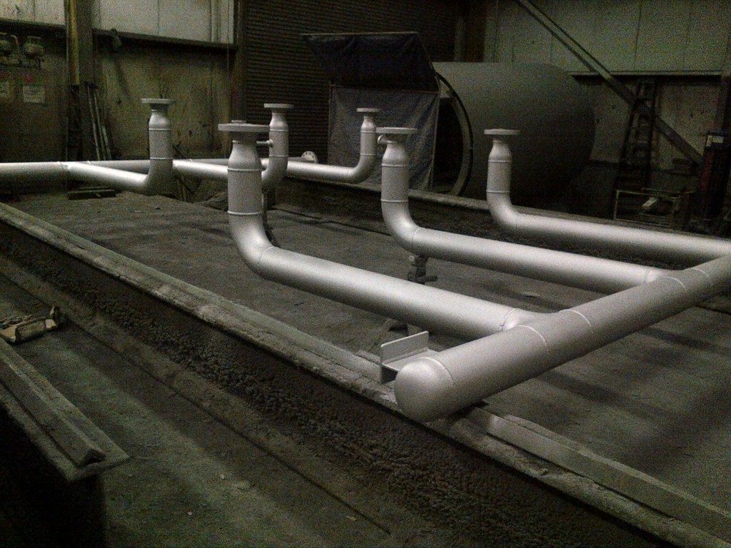 two curved industrial piping components with silver high-temp coating