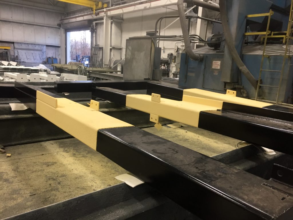 a photo of black metal structural beams coated with a yellow insulative coating