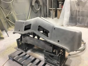 an automotive component is propped on palletes and stripped clean using plastic blasting media