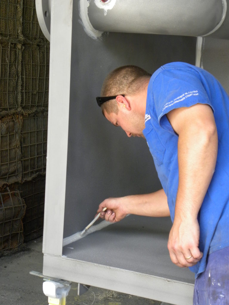 an Inter-City Contracting employee applies stripe coating to the welded areas on a project component