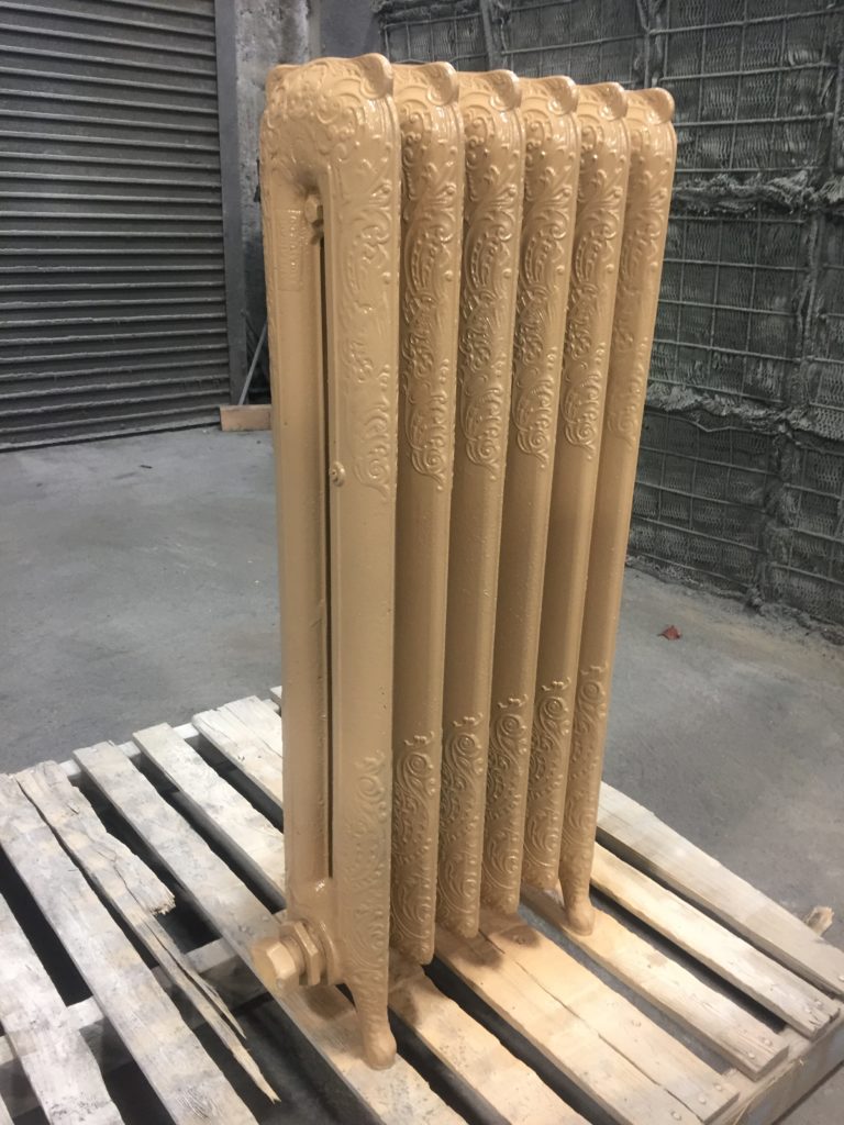 a decorative steam radiator blasted and primed in a light gold color