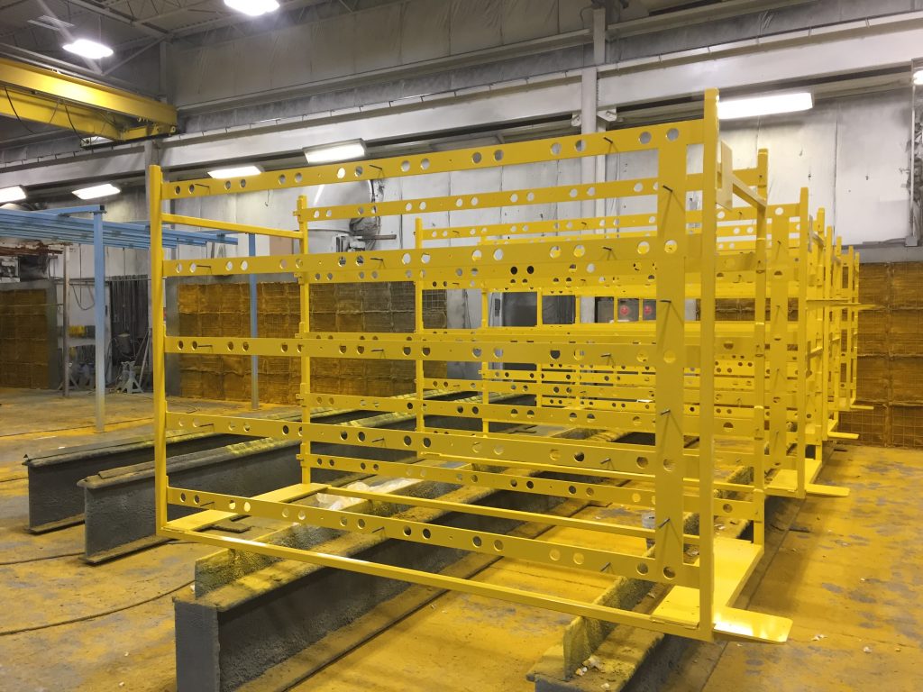 a set of steel frames with a fresh coat of yellow paint are arranged in an Inter-City Contracting workspace